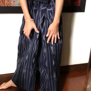 Pu&ograve; includere: Un paio di pantaloni larghi con un motivo a righe blu e bianche. I pantaloni sono realizzati in un tessuto morbido e fluido e hanno una vestibilit&agrave; rilassata.