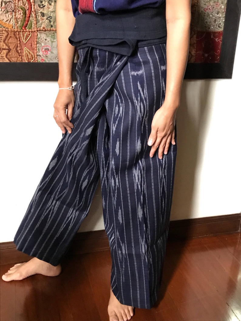Pu&ograve; includere: Un paio di pantaloni blu e bianchi a righe con un motivo geometrico. I pantaloni sono avvolti intorno alla vita e legati nella parte anteriore.