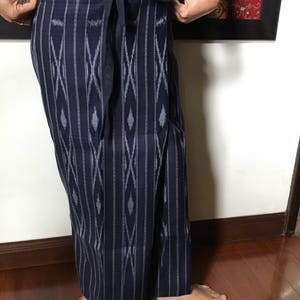 Pu&ograve; includere: Una lunga gonna blu scuro con un motivo geometrico bianco e grigio. La gonna &egrave; avvolta e legata in vita.