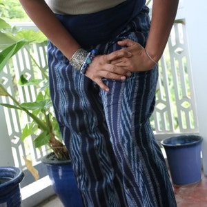 Pu&ograve; includere: Una persona che indossa pantaloni a righe blu e bianche con un braccialetto d'argento e un braccialetto di perline al polso.