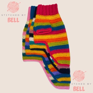 Pode incluir: Vários suéteres coloridos para cães, feitos à mão. Os suéteres apresentam um arco-íris de cores, incluindo vermelho, laranja, amarelo, verde, azul e roxo. O texto "STITCHED BY BELL" é visível na imagem.