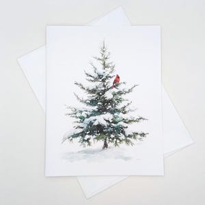 May include: A watercolor illustration of a snow-covered evergreen tree with a bright red cardinal perched on a branch. The image is on a white card with a matching envelope, evoking a winter or holiday theme.