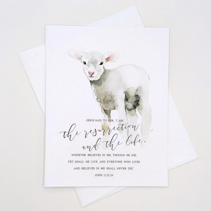 May include: A watercolor greeting card featuring a lamb illustration. The card includes the text "JESUS SAID TO HER. 'I AM the resurrection and the life.'" and a Bible verse from John 11:25,26. The card is paired with a white envelope.