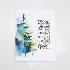 May include: A white greeting card with a watercolor painting of a pine tree in shades of blue, green, and white. The card includes the text "WHAT DOES THE Lord require of you? To act JUSTLY and To love MERCY and To walk HUMBLY with your God MICAH 6:8."