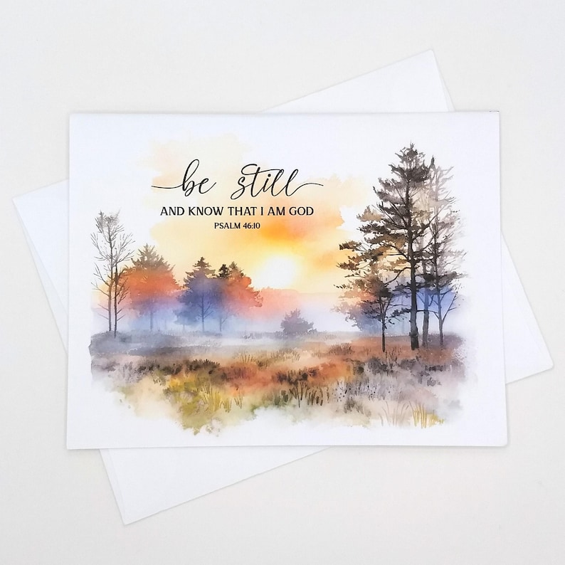 May include: A watercolor painting of a misty forest scene with a sunrise in the background. The text "be still and know that I am God Psalm 46:10" is written in black at the top of the image.