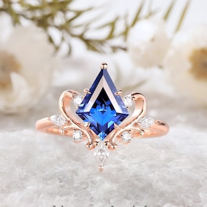 May include: A rose gold engagement ring with a blue sapphire center stone and a delicate floral design. The ring is set with smaller diamonds around the center stone and on the band.