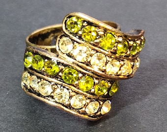 May include: A wrap-style ring featuring a metallic band with a dark finish, adorned with alternating rows of sparkling lime green and clear white round-cut crystals. The design consists of two overlapping bands that create a layered appearance.