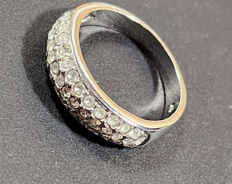 May include: A silver ring with a band of small, clear stones.