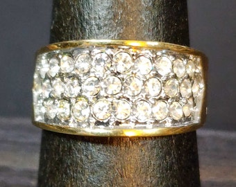 May include: A gold band ring with a wide band of clear rhinestones.