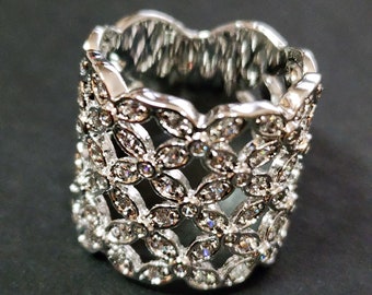 May include: A silver ring with a delicate design of interlocking flower shapes, each adorned with sparkling clear rhinestones.