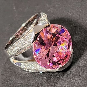 May include: A silver ring with a large pink gemstone surrounded by smaller clear gemstones.