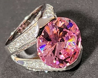 May include: A silver ring with a large pink gemstone surrounded by smaller clear gemstones.