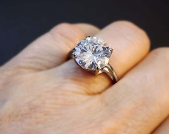May include: A silver ring with a large, clear, round-cut cubic zirconia stone.