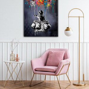 May include: A black and white illustration of a child in a basket, holding onto strings attached to a hot air balloon. The balloon is made of colourful graffiti, including hearts, crowns, and other symbols. The background is a dark blue.