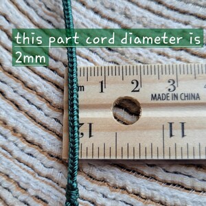 Puede incluir: Primer plano de un cord&oacute;n verde oscuro junto a una regla de madera. El texto de la imagen indica que el di&aacute;metro del cord&oacute;n es de 2 mm. La regla muestra medidas en cent&iacute;metros.