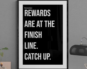 May include: A framed black and white motivational poster with the text "REWARDS ARE AT THE FINISH LINE. CATCH UP." A black desk lamp with a star-shaped decoration sits on a desk with other office supplies.