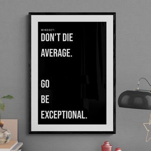 May include: A framed black and white motivational poster with the text "DON'T DIE AVERAGE. GO BE EXCEPTIONAL." A desk lamp with a star-shaped accent and small red jars are also visible.