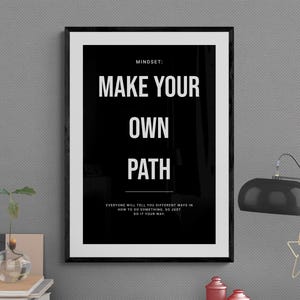 Może przedstawiać: Oprawiony czarno-biały nadruk z napisem "MAKE YOUR OWN PATH". Nadruk znajduje się na biurku z czarną lampą, małymi czerwonymi słoiczkami i małą rośliną w szklanym wazonie. Tekst "MINDSET" znajduje się na górze.