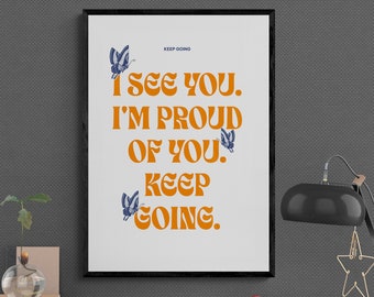 May include: A framed print with a white background and black frame. The print features a motivational quote in orange text that reads "I see you. I'm proud of you. Keep going." with blue butterfly illustrations.