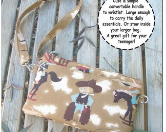 Pode incluir: Uma bolsa Marge bege com uma alça conversível, com uma estampa de cowboy. A bolsa tem um fecho de correr e foi projetada para ser uma pulseira ou guardada dentro de uma bolsa maior. A bolsa é da Mackerilla Design.
