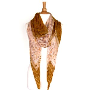 May include: A knitted shawl with a triangular shape, featuring a gradient of colors from mustard yellow to pink. The shawl is draped over a white mannequin.