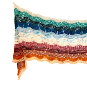May include: A colorful knitted shawl with a wavy pattern in shades of teal, blue, white, pink, brown, and orange.