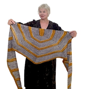 May include: A triangular shawl with a geometric pattern in shades of gray and gold. The shawl is knit with a fine yarn and has a delicate fringe.