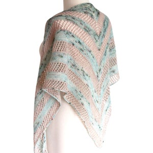 May include: A light blue and pink knitted shawl with a lacy pattern. The shawl is draped over a white mannequin.
