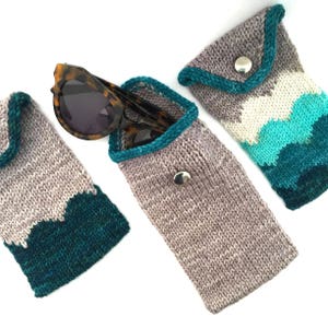 Peut inclure: Trois étuis à lunettes en tricot de couleur sarcelle et gris. Les étuis ont une fermeture à rabat avec un bouton. Un étui contient des lunettes de soleil.