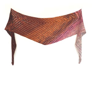 May include: A triangular shawl with a gradient of colours from burgundy to orange to pink. The shawl is crocheted with a delicate stitch pattern.