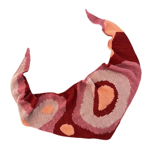 May include: A knitted shawl in shades of red, pink, and peach, with a circular pattern. The shawl has a unique, scalloped edge and is made of soft yarn. This accessory is perfect for adding warmth and style.