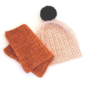 以下が含まれることがあります： 2つのニット帽子のセット。1つは薄いピンクで黒いポンポン付き、もう1つは焦げ茶色です。