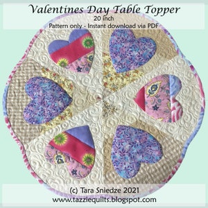 May include: A 20-inch round table topper with a quilted design featuring six hearts in shades of pink, purple, and blue. The hearts are arranged in a circular pattern with a floral print fabric in the center. The text "Valentines Day Table Topper" and "(c) Tara Sniedze 2021" is included in the image.