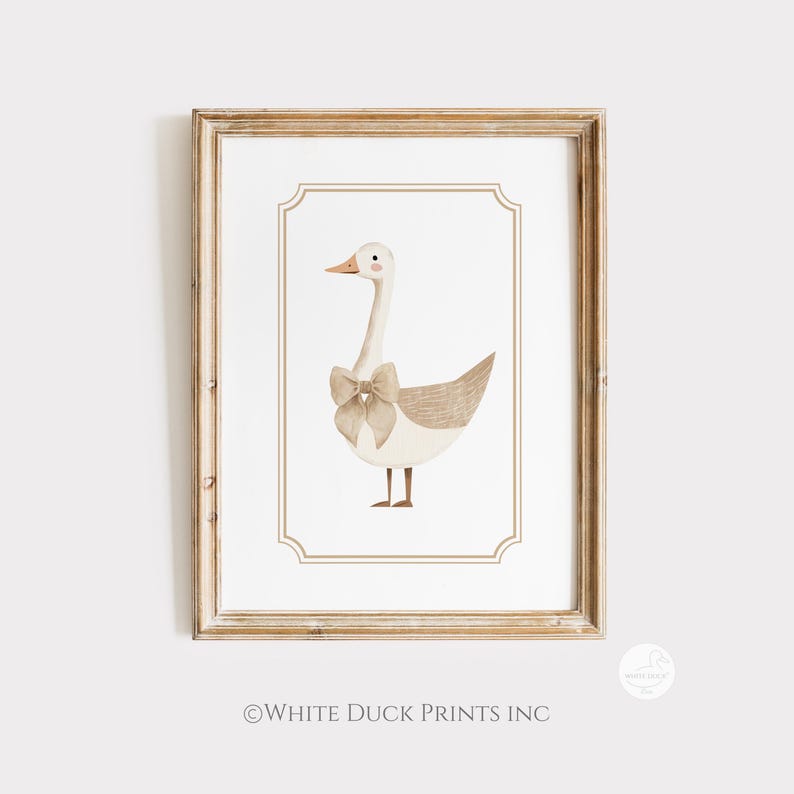 May include: A framed watercolour print featuring a goose with a bow. The goose has a white body, tan wings, and a long neck. The bow is a light tan colour. The print is in a wooden frame with a white background and a decorative border.