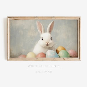 May include: A white rabbit with pink ears sits among a pile of colorful Easter eggs. The rabbit is looking directly at the viewer. The background is a light blue.