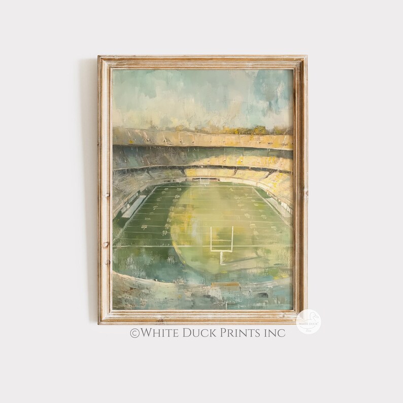 Peut inclure: Une impression encadr&eacute;e d'un stade de football, de style impressionniste. L'&oelig;uvre pr&eacute;sente un terrain vert, des gradins jaunes et un ciel bleu clair. Le cadre est de couleur marron clair. Le texte "WHITE DUCK PRINTS INC" est visible.