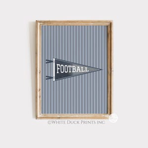 Peut inclure: Impression encadr&eacute;e avec un fanion gris portant le mot "FOOTBALL" en blanc, sur un fond gris &agrave; rayures. L'impression est dans un cadre en bois, adapt&eacute;e &agrave; la d&eacute;coration sur le th&egrave;me du sport.