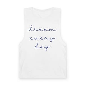 Op de afbeelding: Een wit mouwloos hemd met de tekst "dream every day" in een donkerblauw cursief lettertype, gecentreerd op de voorzijde. Het kledingstuk heeft een ronde halslijn en brede schouderbanden, wat zorgt voor een strak en eenvoudig uiterlijk.