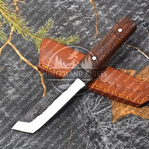 May include: A white-bladed knife with a dark brown wooden handle and a leather sheath. The knife is on a camouflage background with the text "Hinterland Knives" repeated.