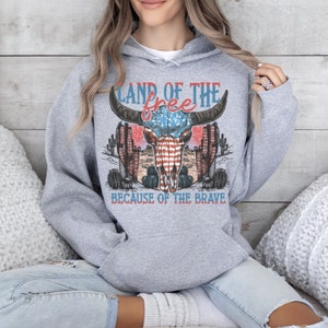 May include: Gray hooded sweatshirt with a graphic print of a bull skull with an American flag design. The text "Land of the free because of the brave" is printed below the skull.