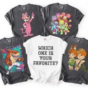 May include: Five graphic t-shirts. Four are dark gray, featuring cartoon characters. The fifth is white, with the text "WHICH ONE IS YOUR FAVORITE?" printed in black. The shirts are folded.