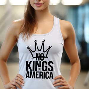 May include: A white vest top featuring a black crown design and the words "NO KINGS IN AMERICA". The sleeveless top has a racerback style. The text is in a bold, sans-serif font.