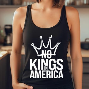 May include: Black vest top featuring a white crown design and the words "NO KINGS IN AMERICA". The top has a scoop neck and is sleeveless. The text is in a bold, sans-serif font.