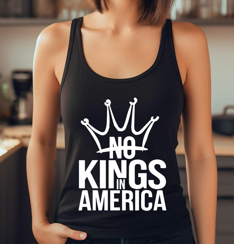 May include: Black vest top featuring a white crown design and the words "NO KINGS IN AMERICA". The top has a scoop neck and is sleeveless. The text is in a bold, sans-serif font.