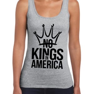 May include: A grey vest top featuring a black crown design and the words "NO KINGS IN AMERICA". The top has a scoop neck and is sleeveless. The graphic is printed in the centre.