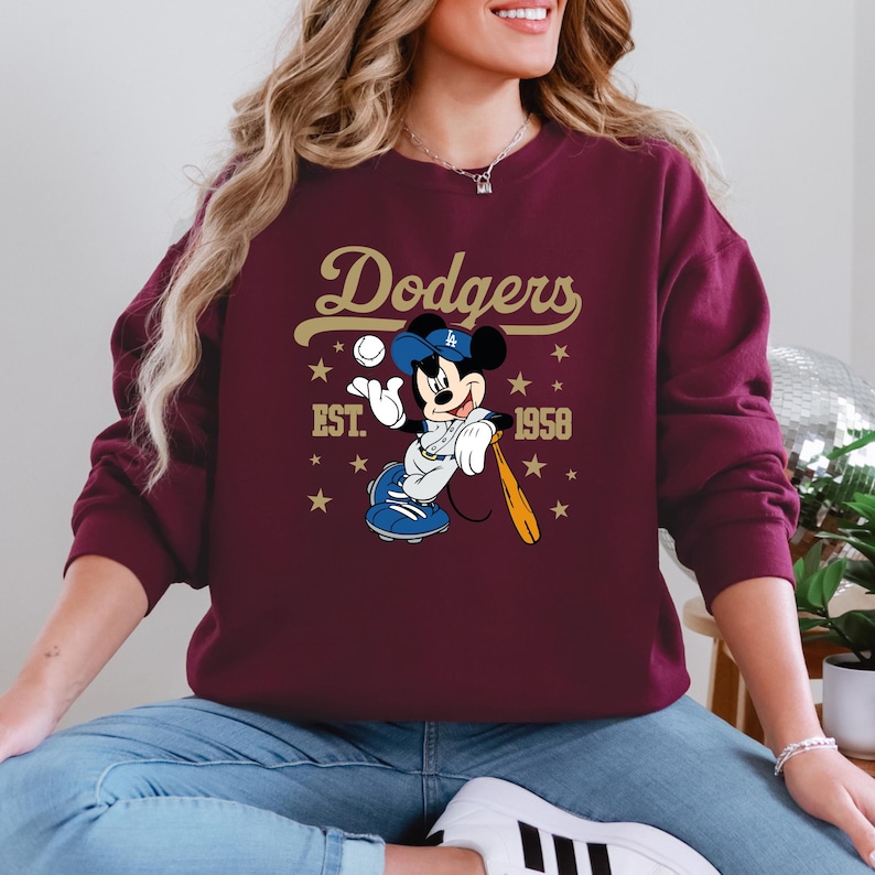 May include: A white ceramic mug with a black handle and the text "But First, Coffee" in a bold, black font. The mug is set against a blurred background. The mug appears to be approximately 10 cm tall.