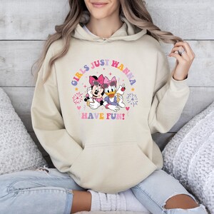 May include: A cream colored hoodie with a graphic of Minnie Mouse and Daisy Duck. The graphic says "Girls Just Wanna Have Fun!" with fireworks and hearts around the characters.