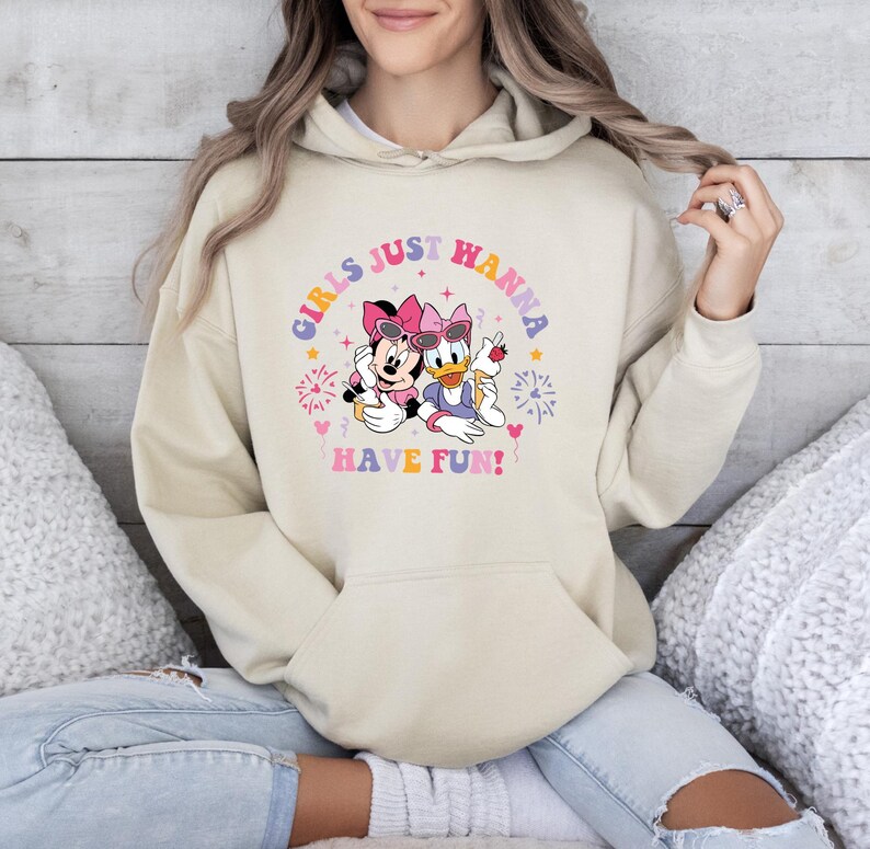 May include: A cream colored hoodie with a graphic of Minnie Mouse and Daisy Duck. The graphic says "Girls Just Wanna Have Fun!" with fireworks and hearts around the characters.