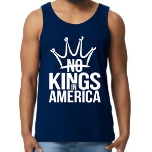 May include: A navy blue vest top featuring the white text "NO KINGS IN AMERICA" under a white crown graphic. The top is sleeveless and made of a soft fabric.