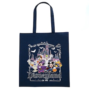 May include: Navy blue tote bag featuring a Disneyland Halloween design. The graphic includes Disney characters in costumes, a castle, bats, and the text "Disneyland Est. 1955". The bag has a rectangular shape and two handles.